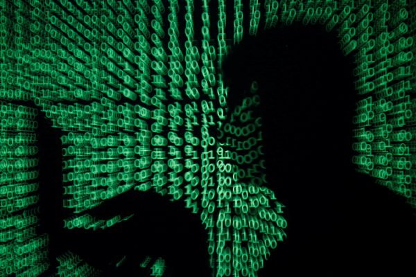 A man holds a laptop computer as cyber code is projected on him in this illustration picture taken on May 13, 2017. Capitalizing on spying tools believed to have been developed by the U.S. National Security Agency, hackers staged a cyber assault with a self-spreading malware that has infected tens of thousands of computers in nearly 100 countries. REUTERS/Kacper Pempel/Illustration
